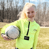 girl wearing a neon green Justice zip up hoodie carrying a soccer ball